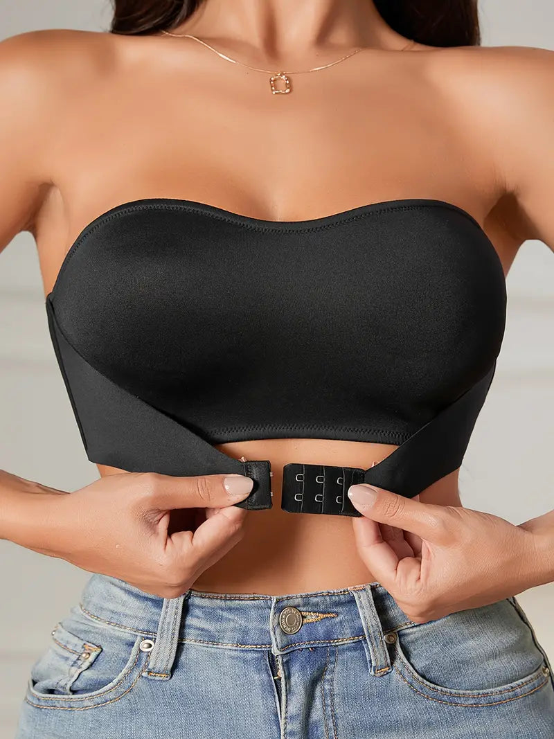 Top nero senza spalline, chiusura frontale a ganci, indossato con jeans. Design elegante e moderno, perfetto per look casual e serate.