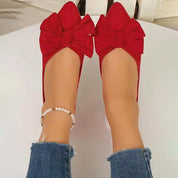 Scarpe ballerine rosse con fiocco, indossate con jeans strappati alla caviglia e cavigliera di perle. Eleganti e alla moda per look casual.