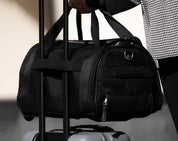 Borsone nero su valigia con ruote, manico telescopico, trasporto facile, viaggio, bagaglio a mano, accessorio da viaggio, tessuto resistente.