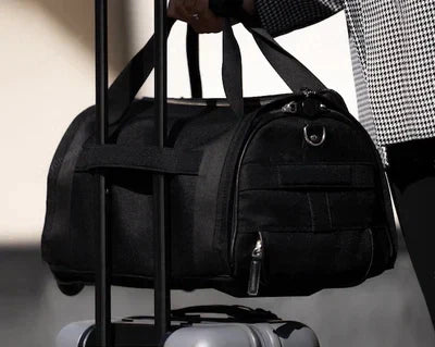 Borsone nero su valigia con ruote, manico telescopico, trasporto facile, viaggio, bagaglio a mano, accessorio da viaggio, tessuto resistente.