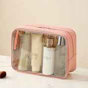 Beauty case rosa trasparente con prodotti cosmetici, ideale per viaggi. Include flaconi di crema e lozione. Organizzatore trucco pratico ed elegante.