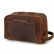 Borsa da toilette in pelle marrone con doppia cerniera, tasca frontale e manico laterale. Elegante e resistente, ideale per viaggi e organizzazione.