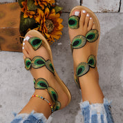 Sandali estivi da donna con decorazioni a piume di pavone, suola beige, indossati con jeans strappati. Scarpe moda casual eleganti.