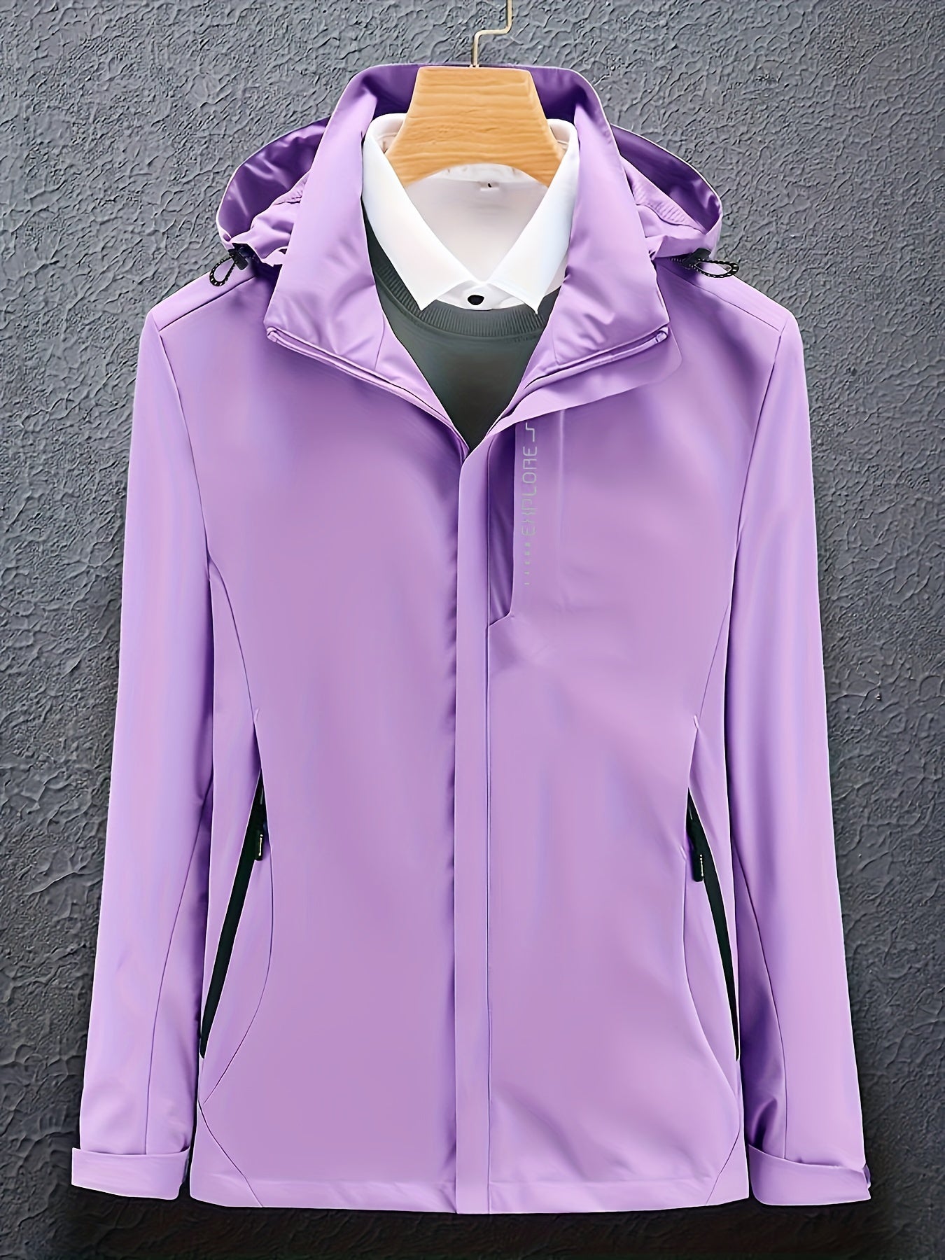 Giacca impermeabile viola da donna con cappuccio, chiusura a zip, tasche laterali, appesa su gruccia. Ideale per outdoor e sport.