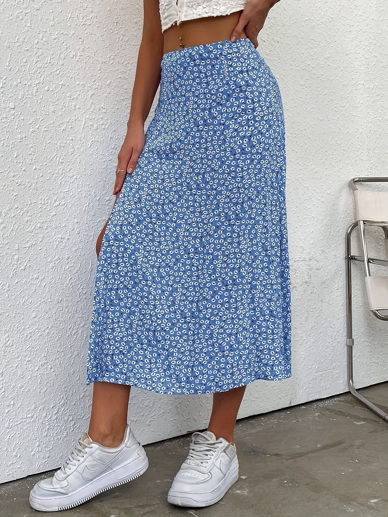 Gonna lunga blu a fiori bianchi, indossata con top bianco e sneakers bianche. Moda estiva casual, stile femminile e trendy.