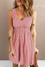 Donna con abito estivo rosa, bottoni frontali, senza maniche, tatuaggi visibili, capelli ondulati. Moda femminile casual, stile estivo elegante.