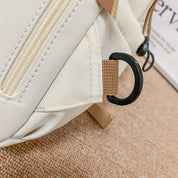 Zaino beige in tessuto con cerniera e gancio nero, dettaglio su cuciture e design moderno. Accessorio moda pratico e versatile.