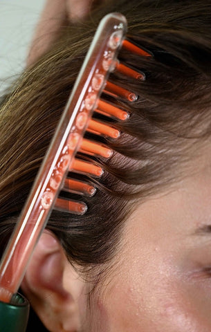 Pettine elettrico per terapia ad alta frequenza su capelli castani, trattamento per la crescita dei capelli e salute del cuoio capelluto.