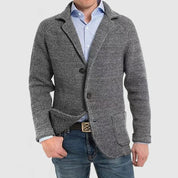 Giacca cardigan uomo grigia in maglia, stile casual elegante, con bottoni e tasche frontali, indossata su camicia azzurra e jeans.