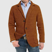 Giacca uomo marrone in maglia, stile casual elegante, con bottoni e tasche, indossata su camicia azzurra e jeans. Moda autunnale maschile.