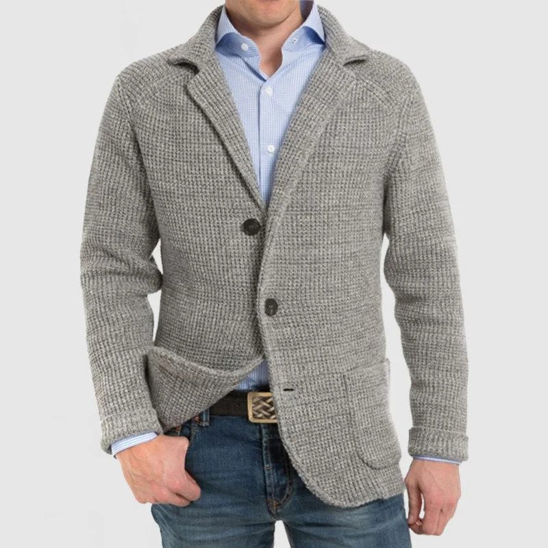 Giacca cardigan uomo grigia in maglia, stile casual elegante, con bottoni e tasche frontali, indossata su camicia azzurra e jeans.