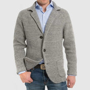 Giacca cardigan uomo grigia in maglia, stile casual elegante, con bottoni e tasche frontali, indossata su camicia azzurra e jeans.
