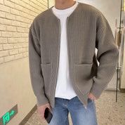 Giacca cardigan uomo in maglia grigia, stile casual, con tasche frontali, indossata su t-shirt bianca e jeans. Moda autunnale maschile.