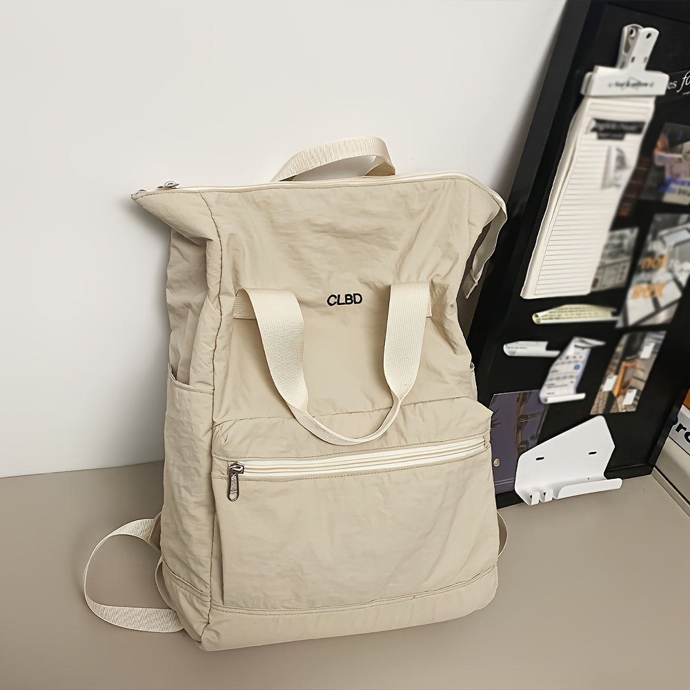 Zaino beige in tessuto resistente con tasca frontale con zip, manici e spallacci regolabili, appoggiato su scrivania moderna.