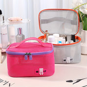 Due beauty case in rete, uno rosa e uno grigio, con cerniera e manico, contenenti cosmetici. Ideali per organizzare trucchi e accessori da viaggio.