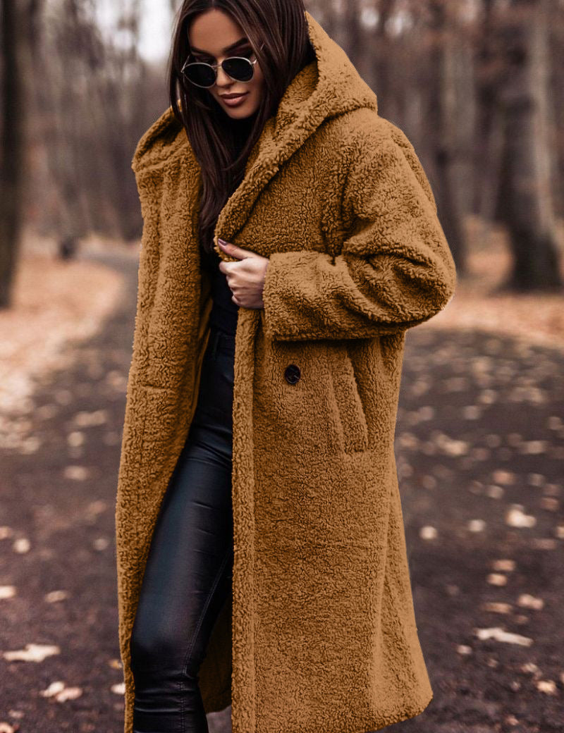 Donna con cappotto teddy marrone, occhiali da sole neri, pantaloni in pelle nera, passeggia in un parco autunnale. Moda invernale, stile casual chic.