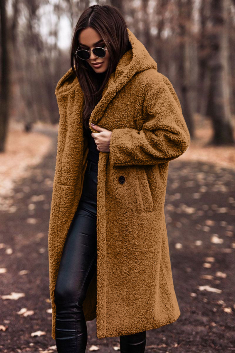 Donna con cappotto teddy marrone, occhiali da sole neri, pantaloni in pelle nera, passeggia in un parco autunnale. Moda invernale, stile casual chic.