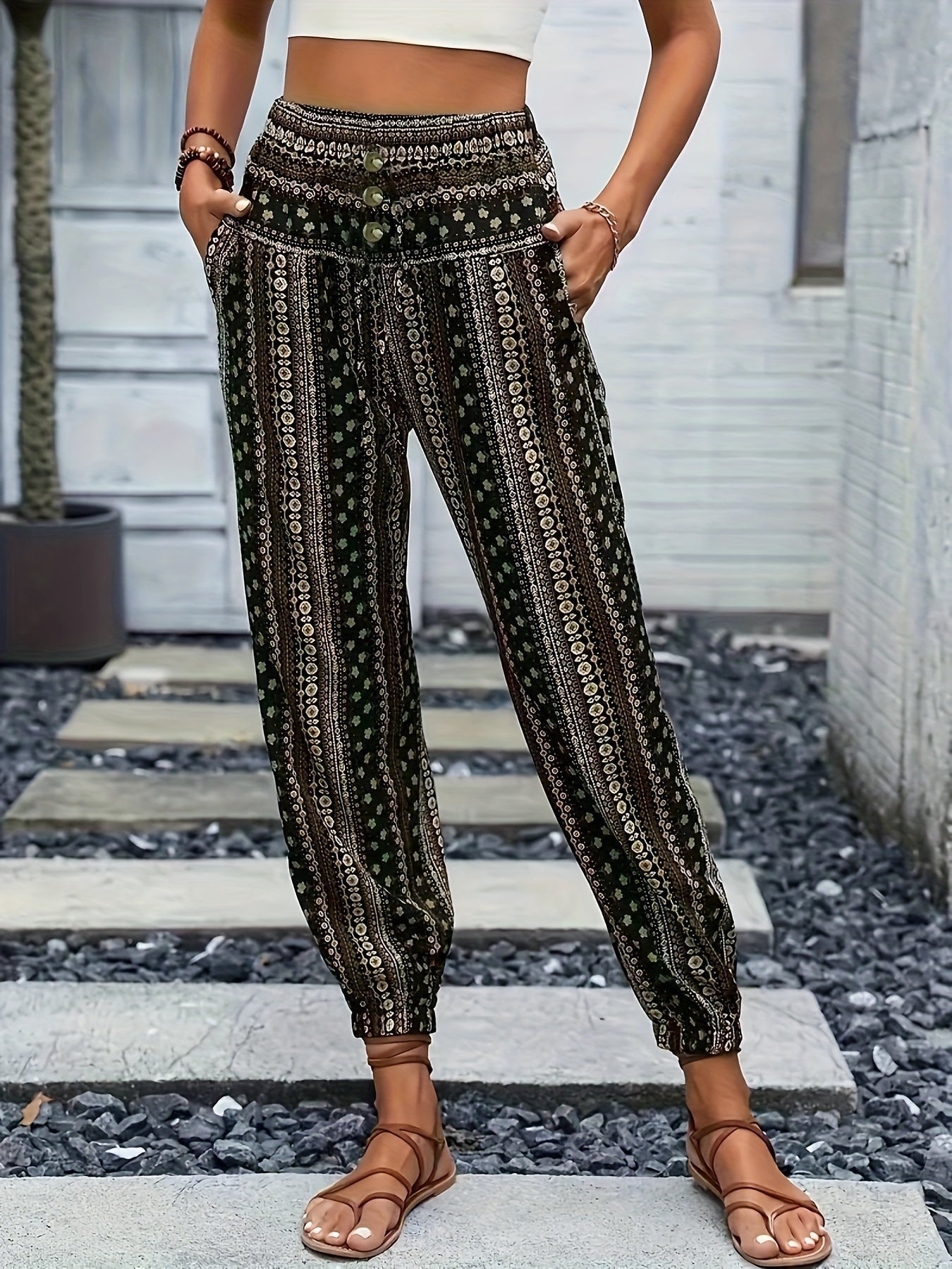 Pantaloni boho donna a vita alta, motivo etnico, tasche laterali, fondo elastico, stile casual estivo, indossati con sandali marroni.