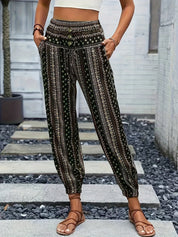Pantaloni boho donna a vita alta, motivo etnico, tasche laterali, fondo elastico, stile casual estivo, indossati con sandali marroni.