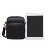 Borsa a tracolla in pelle nera accanto a tablet, design elegante e compatto, ideale per uomo, accessorio moda, perfetto per lavoro e viaggio.