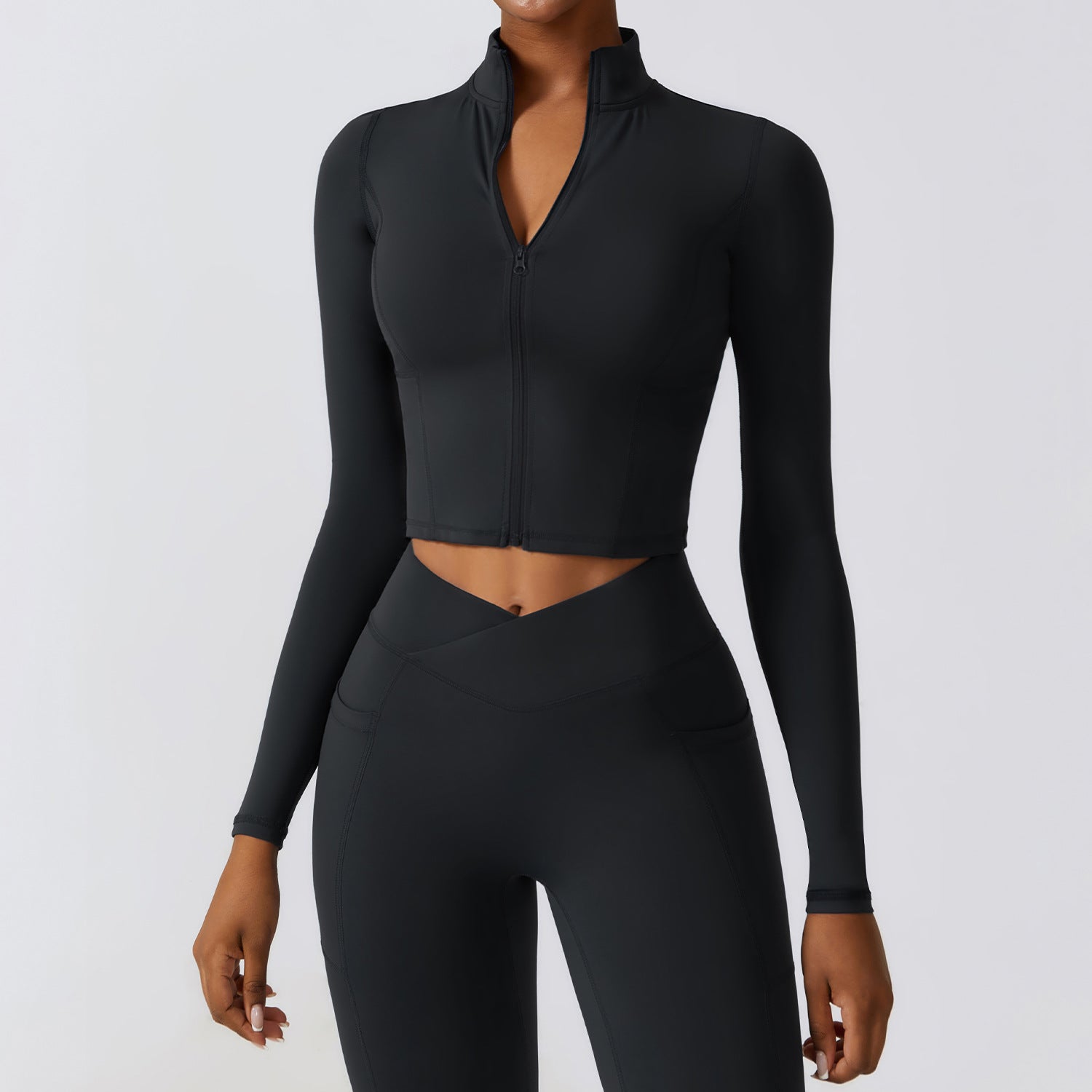 Giacca sportiva nera da donna a maniche lunghe con zip, abbinata a leggings a vita alta. Abbigliamento fitness elegante e funzionale.