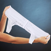 Mani che tengono slip bianchi in pizzo su sfondo blu. Intimo femminile elegante, lingerie di lusso, moda donna.