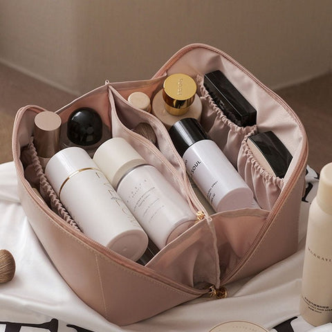 Beauty case rosa aperto con prodotti cosmetici e skincare, flaconi e barattoli organizzati. Accessori trucco, borsa da viaggio elegante e funzionale.