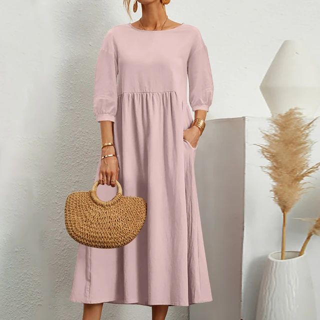 Abito lungo rosa donna, maniche a tre quarti, tasche laterali, borsa paglia intrecciata, stile casual elegante, sfondo bianco minimalista.
