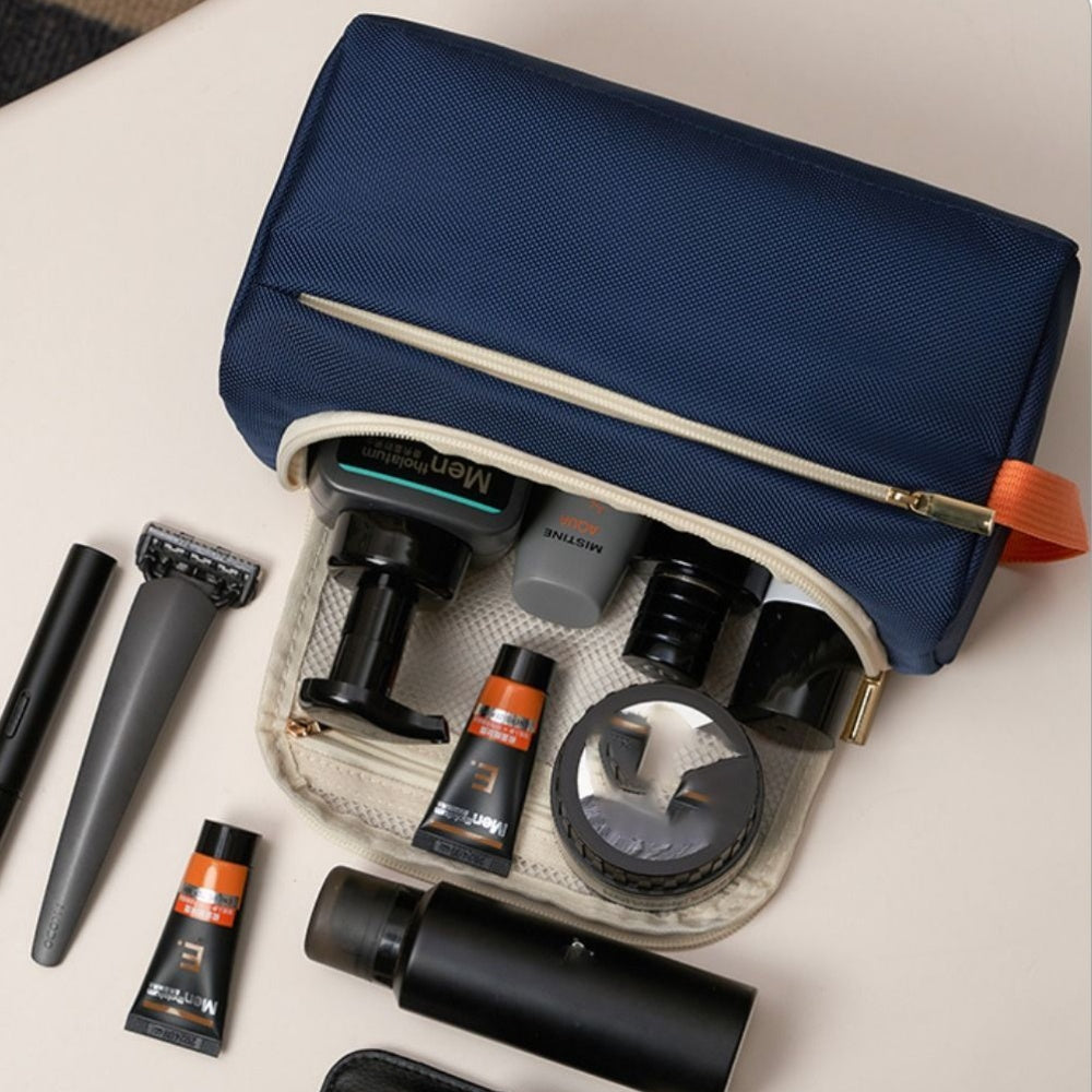 Beauty case blu con zip aperta, contenente prodotti per la cura personale come crema, rasoio e flaconi. Accessori da viaggio essenziali per uomo.