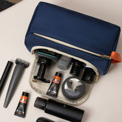 Beauty case blu con zip aperta, contenente prodotti per la cura personale come crema, rasoio e flaconi. Accessori da viaggio essenziali per uomo.