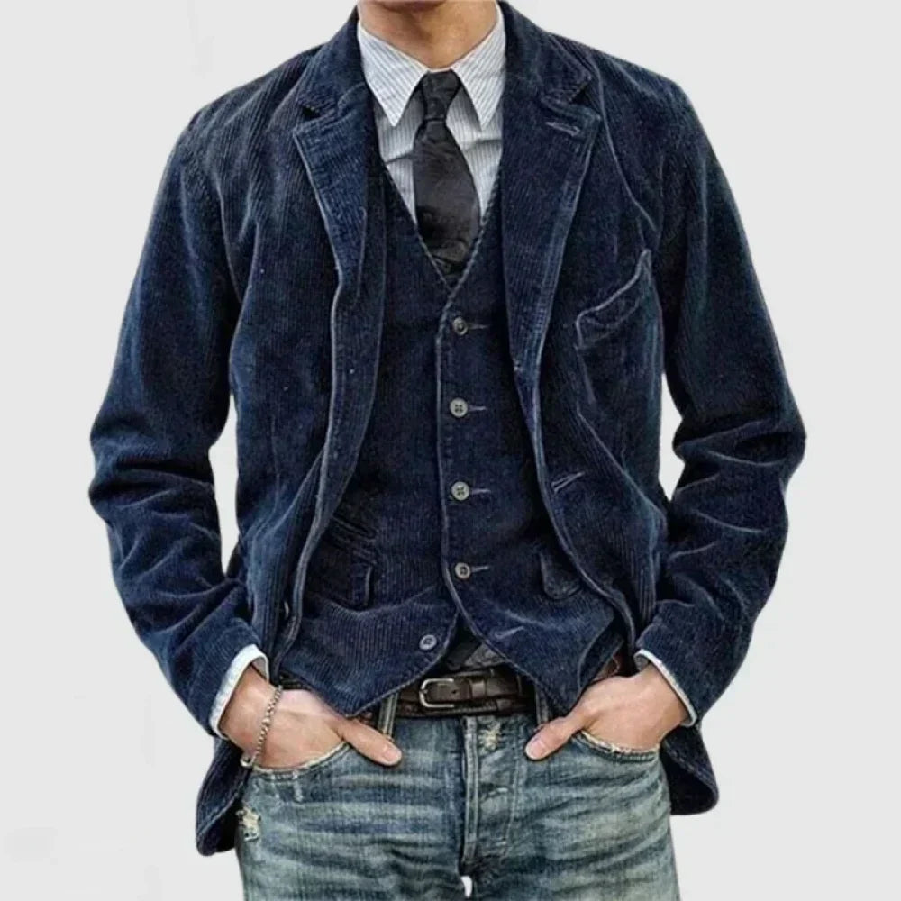 Giacca uomo in velluto blu, abbinata a gilet e cravatta nera, su camicia a righe. Look casual elegante, moda maschile autunno inverno.