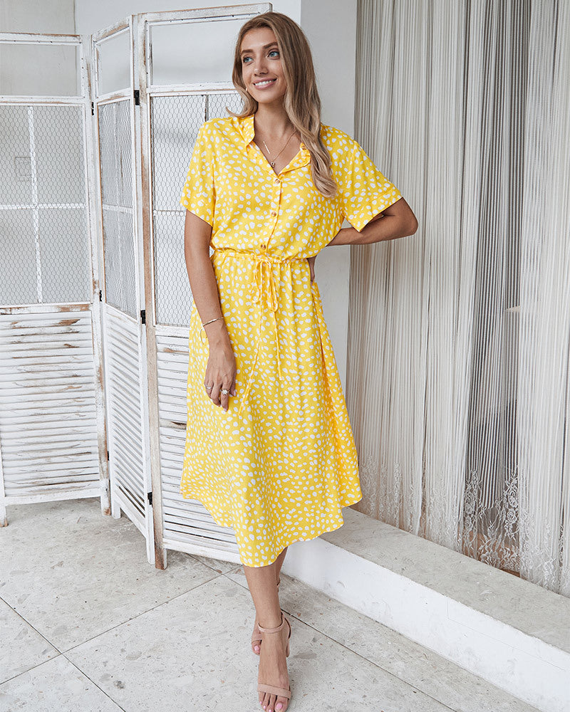 Abito estivo giallo a pois bianchi, maniche corte, cintura in vita, indossato da donna sorridente. Moda femminile, abbigliamento casual elegante.