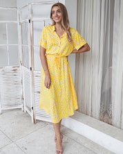 Abito estivo giallo a pois bianchi, maniche corte, cintura in vita, indossato da donna sorridente. Moda femminile, abbigliamento casual elegante.