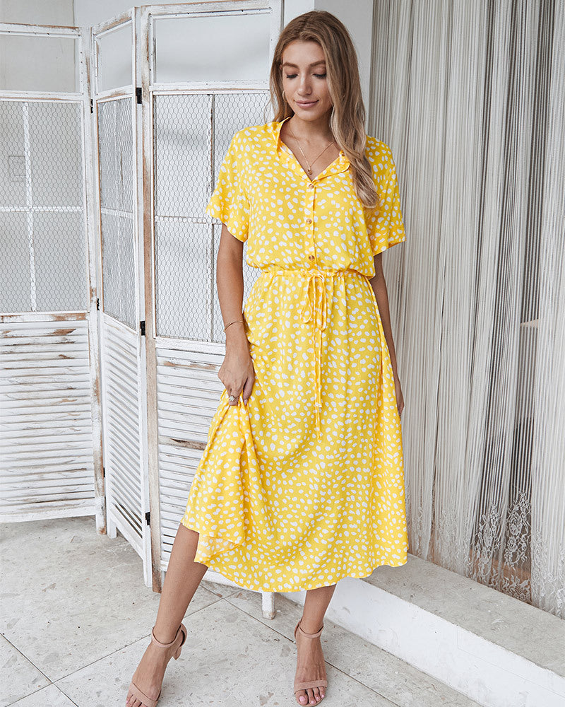 Donna con abito lungo giallo a pois bianchi, maniche corte, colletto e cintura in vita. Moda estiva, abbigliamento casual elegante.