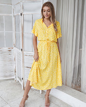 Donna con abito lungo giallo a pois bianchi, maniche corte, colletto e cintura in vita. Moda estiva, abbigliamento casual elegante.
