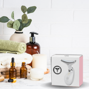Scatola di massaggiatore viso a forma di Y su tavolo da bagno con asciugamani, candele e flaconi. Cura della pelle, bellezza, benessere.