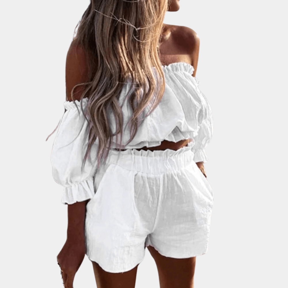 Donna con top e shorts bianchi, spalle scoperte, tessuto leggero. Moda estiva, abbigliamento casual elegante, look fresco e trendy.