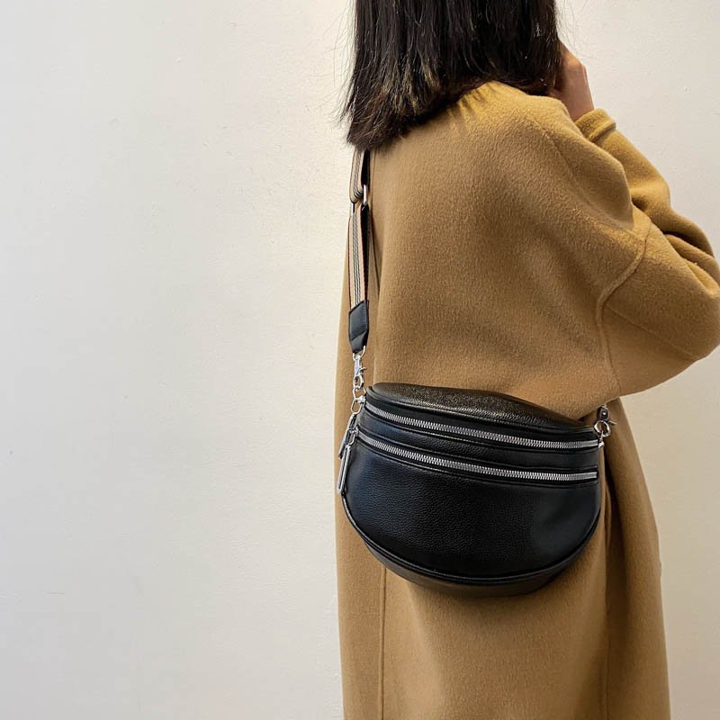 Donna con cappotto beige indossa marsupio nero in pelle, moda autunno inverno, accessorio trendy, borsa a tracolla casual elegante.