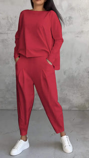 Completo donna rosso elegante, maglia a maniche lunghe e pantaloni larghi, abbinato a sneakers bianche. Moda casual chic, abbigliamento femminile.
