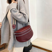 Donna con borsa a tracolla bordeaux in pelle, indossa cardigan grigio e abito beige. Moda autunnale, accessori eleganti, stile casual chic.
