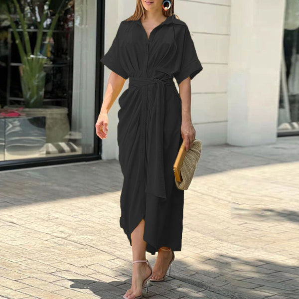 Abito lungo nero elegante con cintura, maniche corte, indossato da donna con sandali e borsa paglia. Perfetto per moda estiva e look casual chic.
