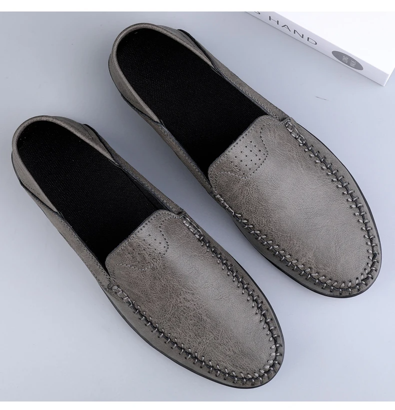 Mocassini uomo in pelle grigia, cuciture a vista, suola nera antiscivolo. Scarpe eleganti e comode, ideali per look casual e formali.
