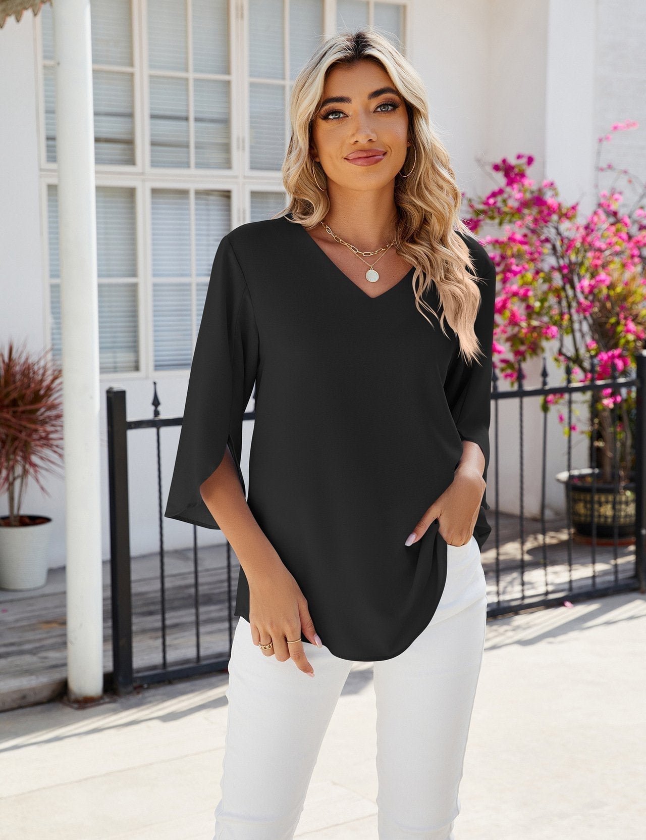 Blusa nera elegante da donna con scollo a V, maniche a tre quarti, abbinata a pantaloni bianchi. Moda femminile estiva, look casual chic.