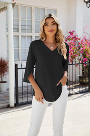 Blusa nera elegante da donna con scollo a V, maniche a tre quarti, abbinata a pantaloni bianchi. Moda femminile estiva, look casual chic.