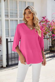 Donna con maglia rosa a maniche lunghe, pantaloni bianchi, collana dorata, sfondo con fiori e finestra. Moda femminile estiva elegante.