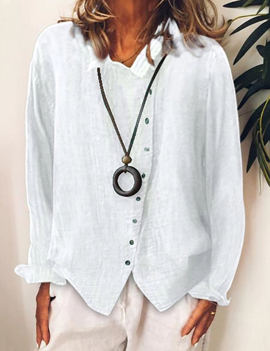 Camicia bianca in lino da donna con bottoni verdi, abbinata a collana con ciondolo circolare. Moda casual elegante, perfetta per l'estate.