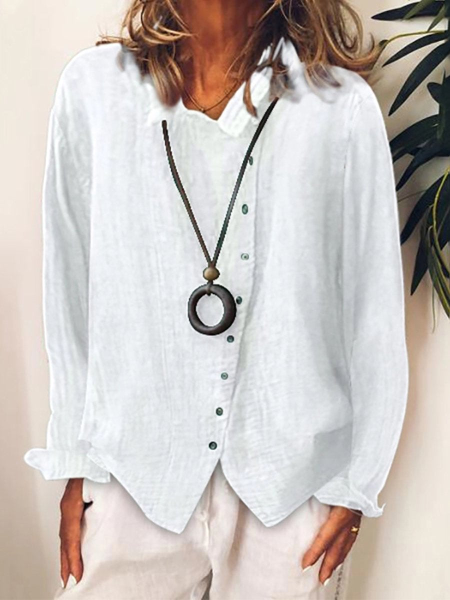 Camicia bianca in lino da donna con bottoni verdi, abbinata a collana con ciondolo circolare. Moda casual elegante, perfetta per l'estate.