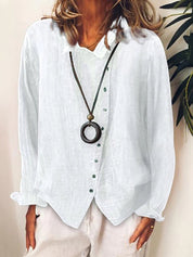 Camicia bianca in lino da donna con bottoni verdi, abbinata a collana con ciondolo circolare. Moda casual elegante, perfetta per l'estate.