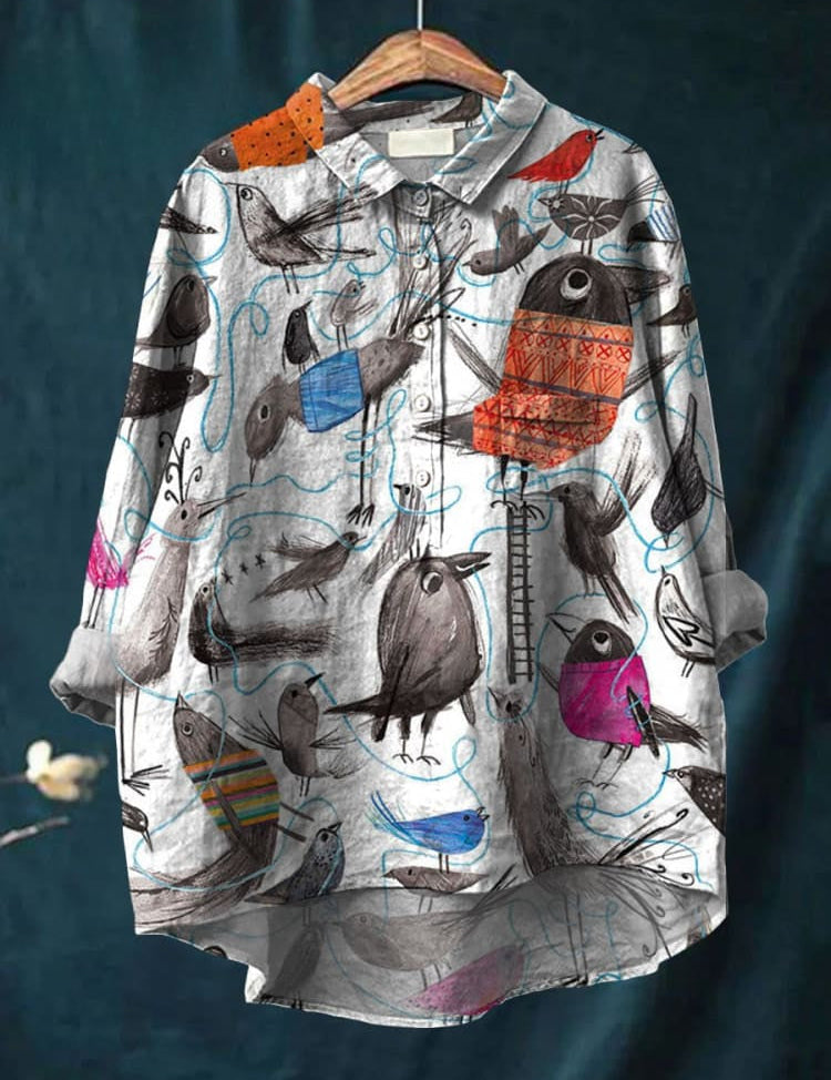 Camicia donna con stampa uccelli colorati, maniche lunghe, colletto classico, design artistico su sfondo bianco, moda casual elegante.