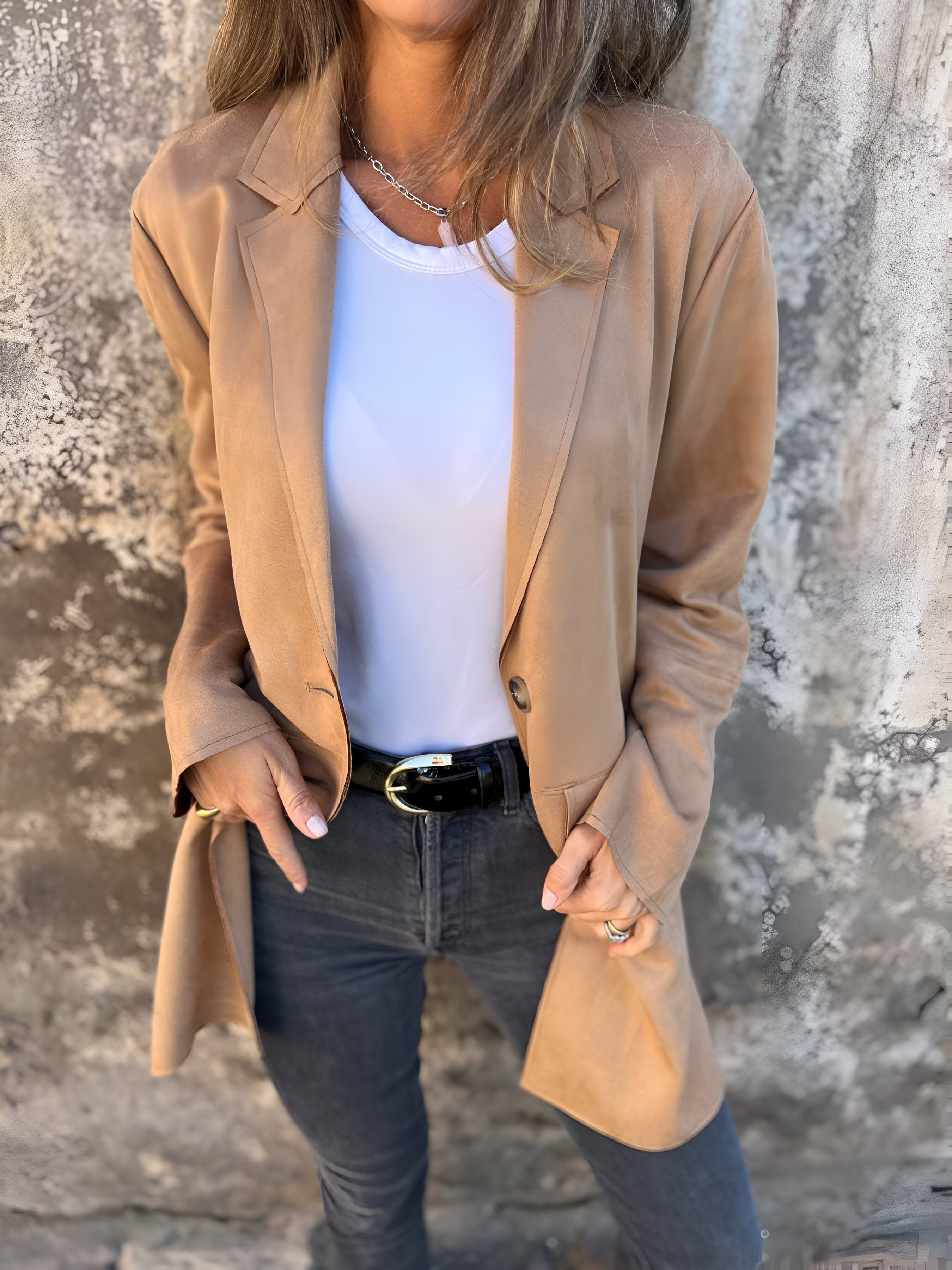 Donna con giacca beige, maglietta bianca e jeans neri. Moda casual elegante, abbigliamento autunnale, stile urbano femminile.